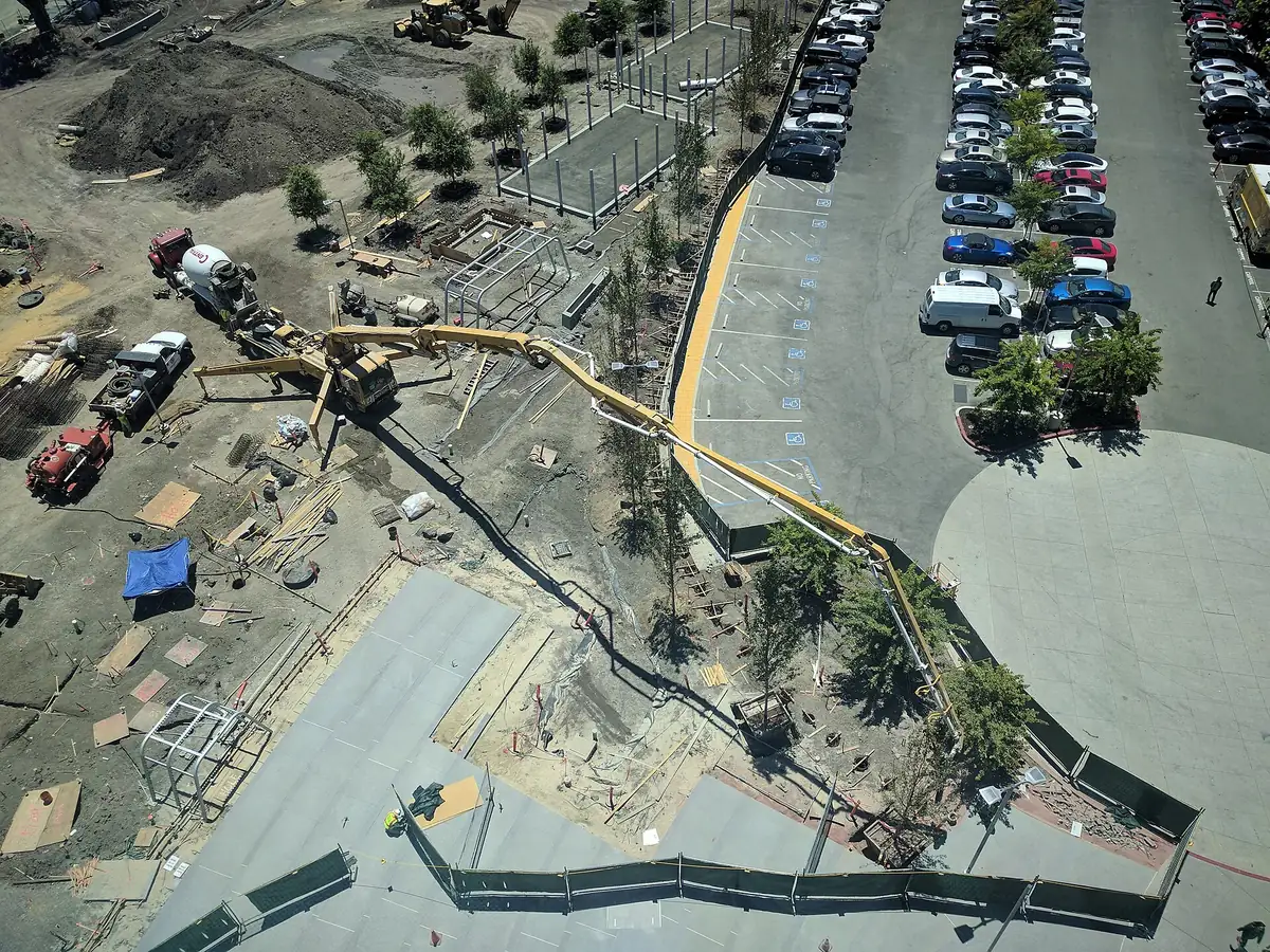 Aerial view of a boom pump with its boom stretched across a construction site