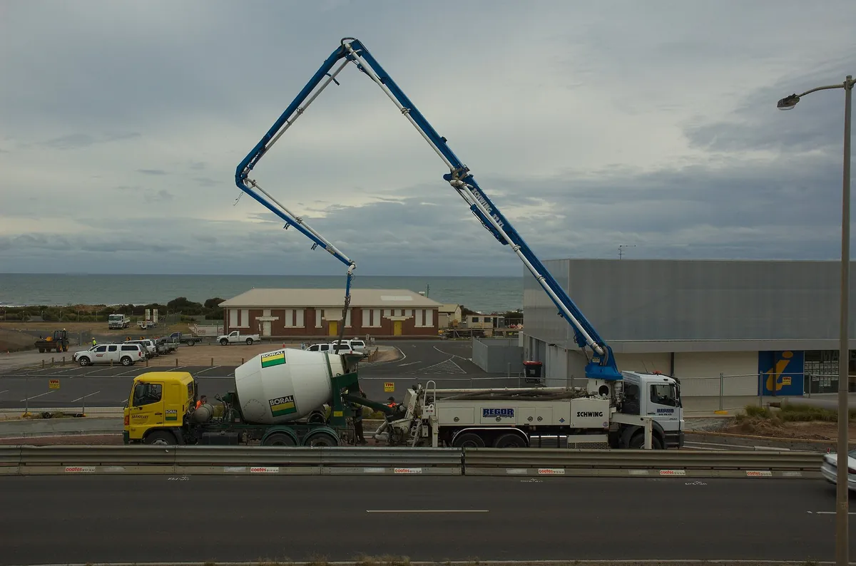 Side view of a concrete pump truck with its boom folded up, next to a mixer truck